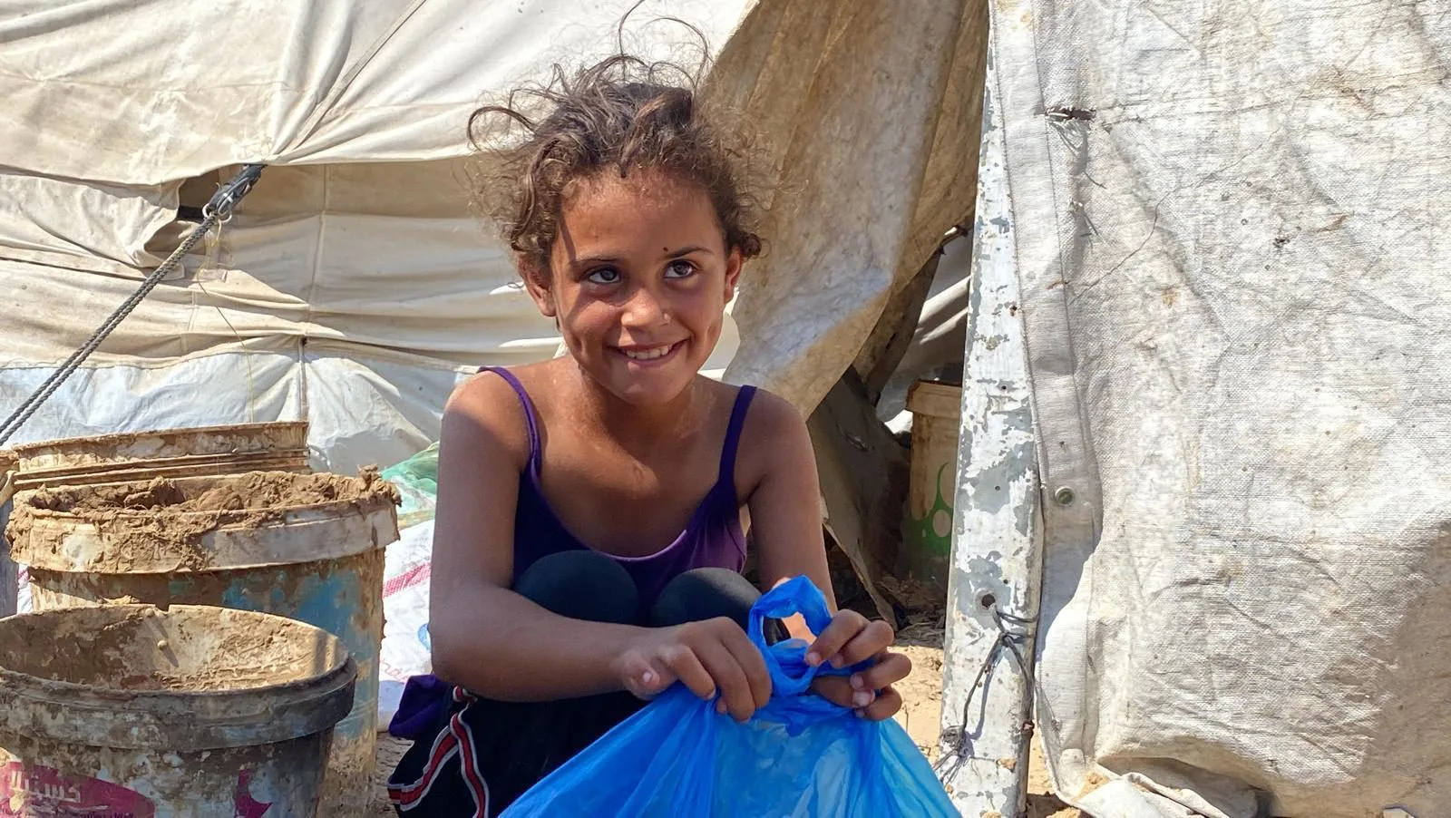 A girl in Gaza smiles holding a Elif aid parcel